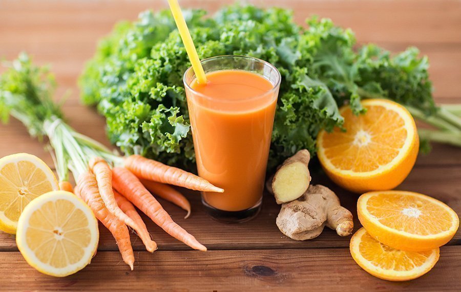 Ein Glas mit Karottensaft und frisches Obst und Gemüse