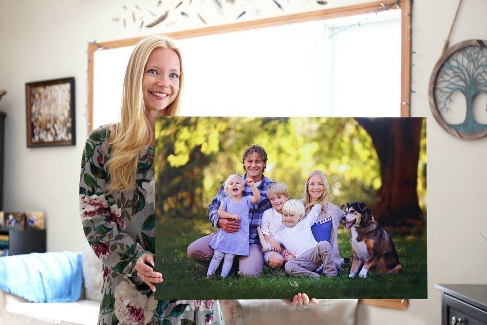 Frau mit einer großen Fotoleinwand mit Familienfoto in der Hand
