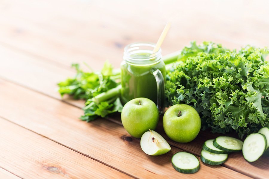 Grüner Saft im Henkelglas mit grünem Obst und Gemüse auf Holztisch