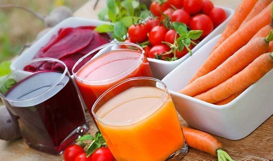 Frische Karotten und Tomaten und deren Saft aus dem Entsafter